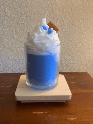 A blue drink with whipped cream and cookie on top.