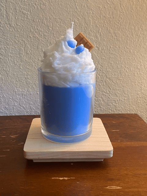 A blue drink with whipped cream and cookie on top.