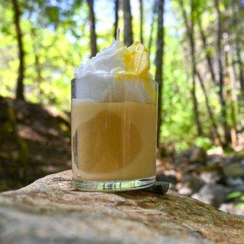 A glass of coffee with whipped cream on top.