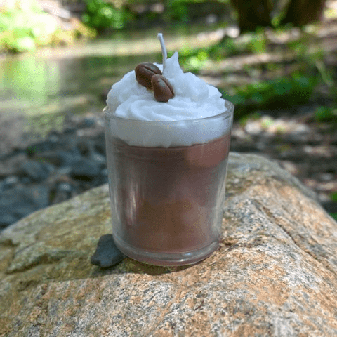 A candle is sitting on the rock near water.