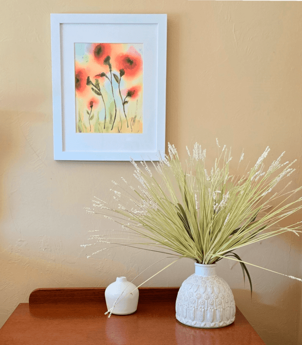 A white vase with some grass in it