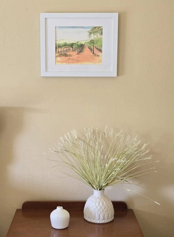 A white vase with some green plants in it