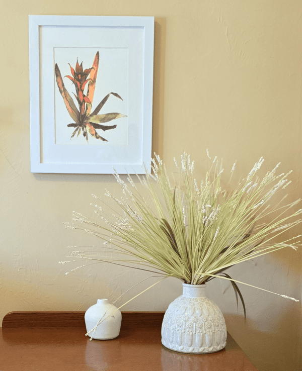 A white vase with some green plants in it