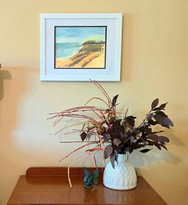 A vase of flowers on the table in front of a painting.