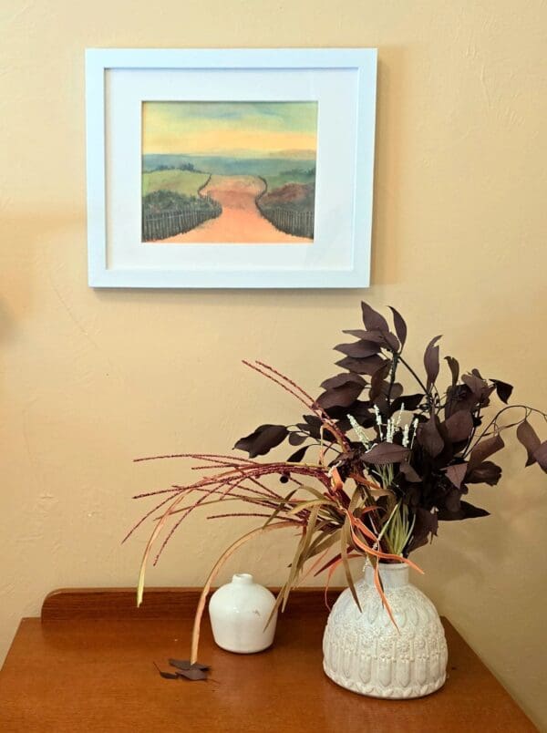 A vase of flowers on the table in front of a painting.