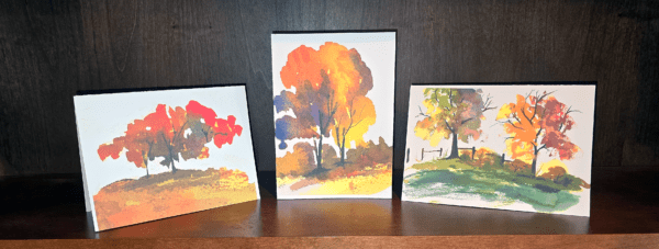 Three paintings of trees on a table