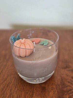 Pumpkin candle in a glass holder.